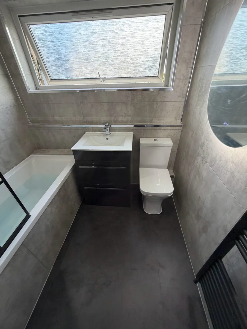Fitted bath with black shower screen and dark vanity